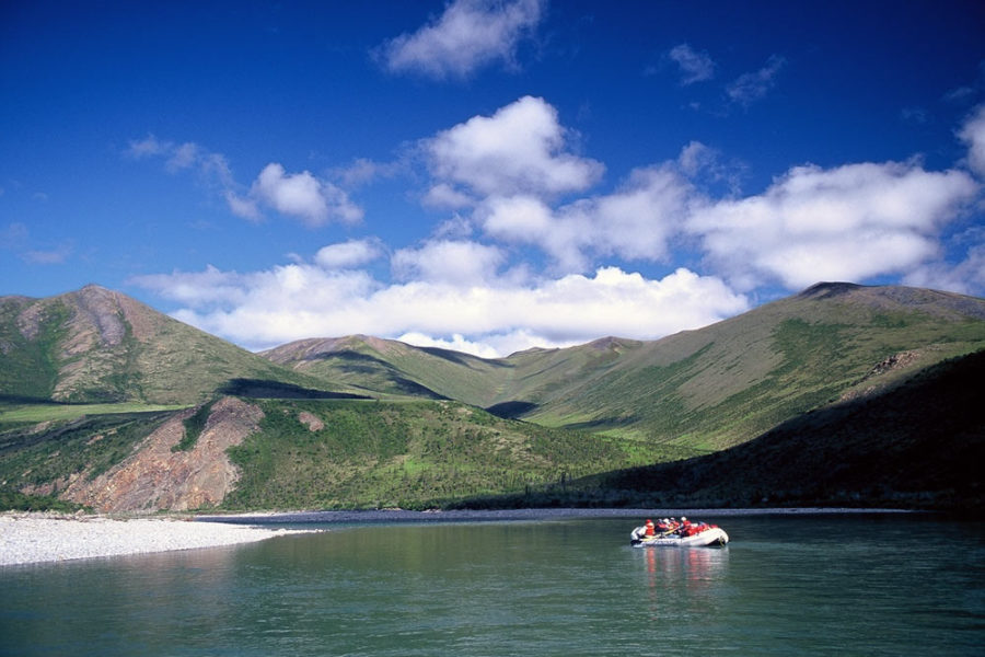 Raft on river with mountains in backdrop, Firth River Rafting, Ivvavik National Park, Yukon Territory.