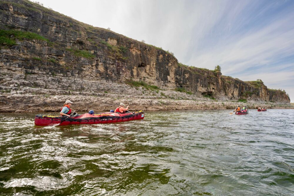 Three canoes navigating a scenic canyon stretch on the Horton River during an expedition.