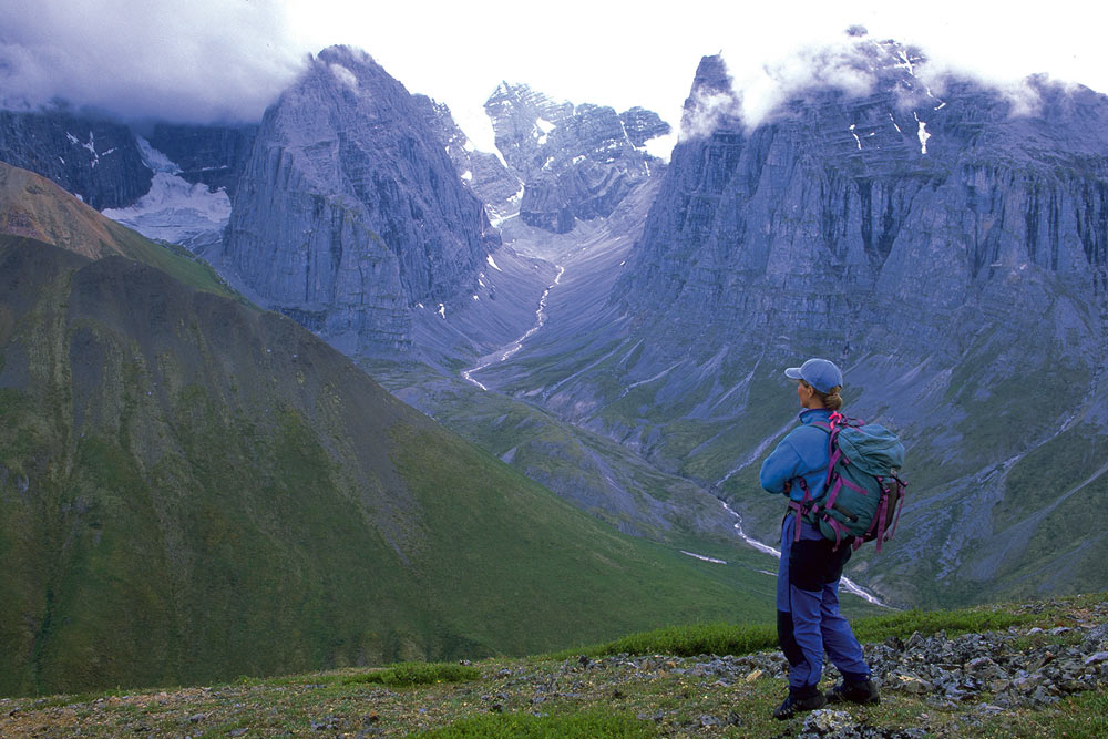 A hiker taking in an incredible Mountain View, high above the Snake River in Yukon, Canada.