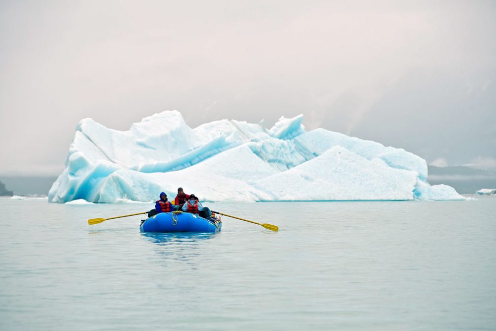 Rafter on lake with iceberg on our Alsek River Rafting Expedition.