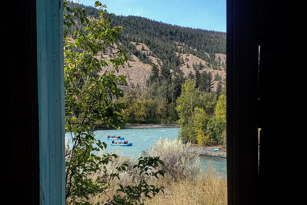 Photo: Looking through a window frame at two rafts descending a set of rapids.
