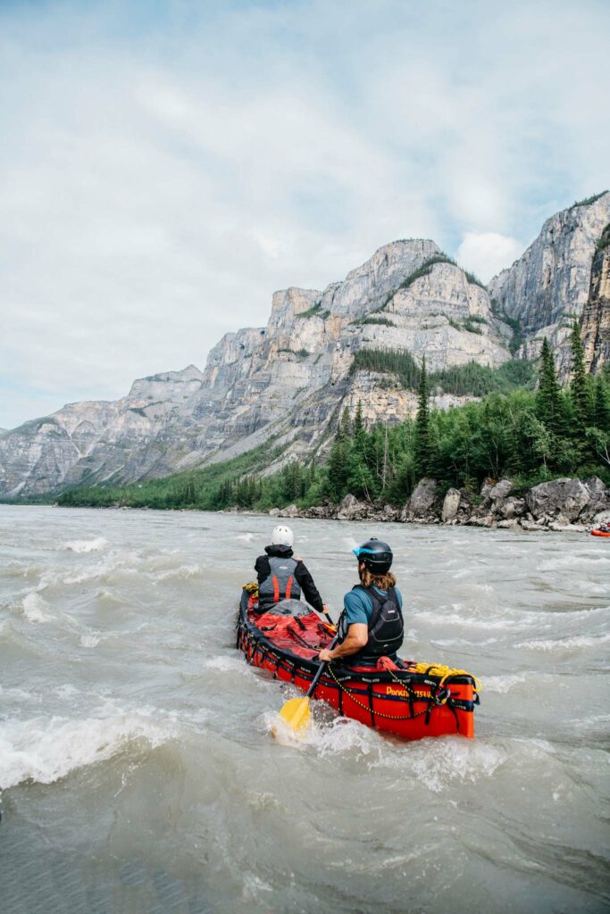 Two paddlers canoeing through rapids on the Nahanni River