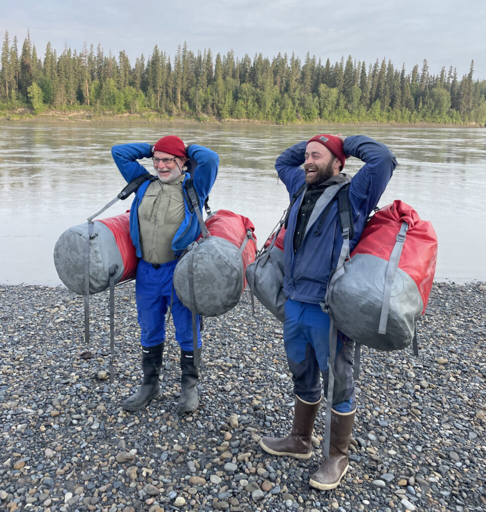 Rafters carrying dry bags wearing rubber boots.